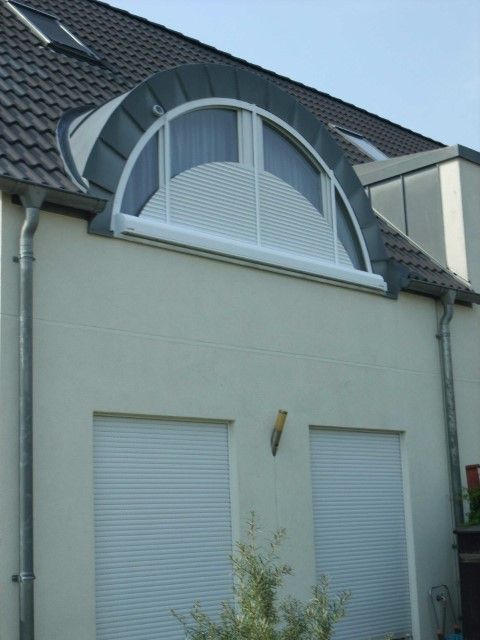 Wohnhaus mit geschlossenen Rollläden, auch am Rundbogenfenster im Dach